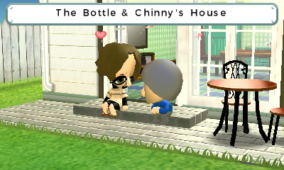 The Bottle and Chinny outside their house on their backyard patio. Both of them are sitting together, looking at each other as heart particles fly above them.